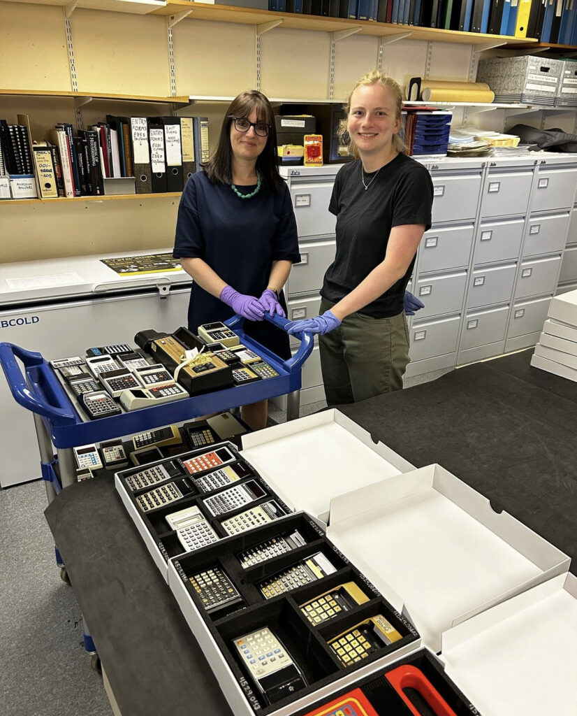 Two women - Morgan Bell and Clare Rogowski - stand in front the new storage for the calculator collection at the Whipple Museum.