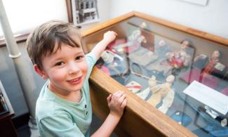 Little boy looking at a glass case of objects