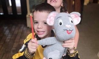 Boy and girl posing in museum with large knitted mouse