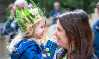 Image of a mother and child. The child is wearing a crown made of plants.