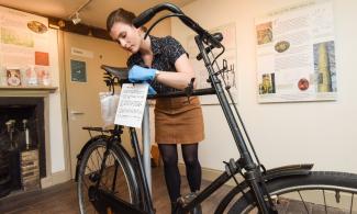 Image of museum conservation person cleaning a bike exhibit 