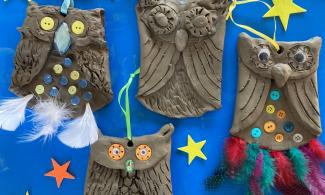 Four decorative clay owls set against a blue background