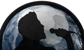 Silhouette of a man with a microphone against a background of the planet Earth