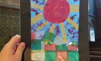 Child's hand holding tissue collage artwork