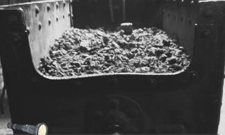 Black and white image of interior of museum with barrow of coal