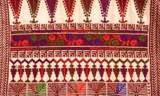 Red, green, purple and orange embroidery on white cloth.
