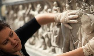 Woman wearing gloves touches a plaster relief