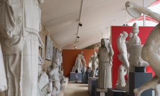 A gallery filled with statues, with a child standing in the background