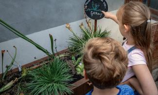 A young boy and girl look at carnivorous plants with a sign that reads 'please be gentle, we bite'