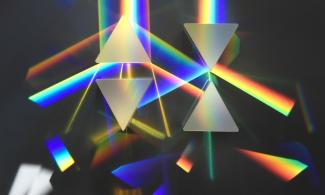 A series of prisms with light shining through them to make rainbow colours 