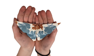 a patterned paper origami butterfly, held carefully in a child's hands