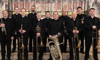 A group of men dressed in black and holding brass instruments.