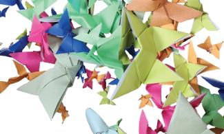 A swathe of brightly coloured, paper origami butterflies, of different sizes, on a white background.