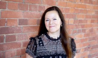 a woman looking at the camera with a brick wall background