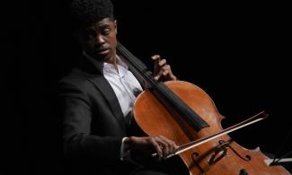 Man sits in shadow playing cello