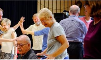 A group of people standing, dancing and smiling in a room.