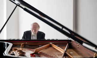 A man sits at an open piano.