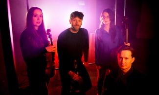 A group of 4 people shrouded in a purple light