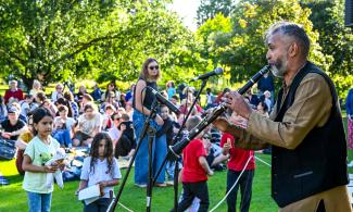 A male clarinettist performs to a crowd in the sunshine.