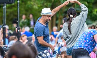 A couple dance amongst a crowd of people enjoying music in the Garden.