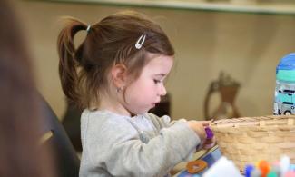 alt= "a young girl with brown hair plays with arts and crafts supplies"