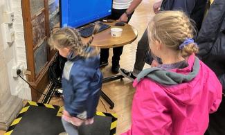 Two children jump and look at a screen, as they 'jump to make an earthquake'