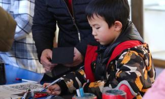 alt="a mother and son carry out arts and crafts in the museum space"