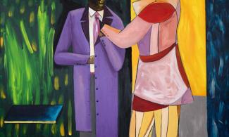 Two men standing outside of a shopfront in brightly coloured clothing.