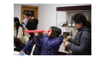 Young visitor using a red telescope in the Learning Gallery at the Whipple Museum.