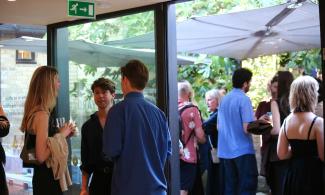 A group of people smiling and talking in the courtyard at Kettle's Yard.