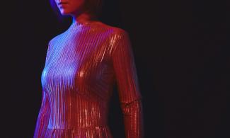 A woman in a silver dress illuminated by a red light.