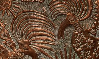 Close up of beaten copper plate depicting stylised birds of paradise