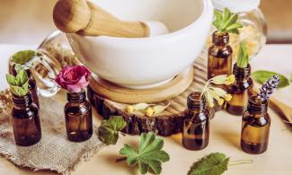 Brown glass bottles with flowers and plants in, around a white bowl.