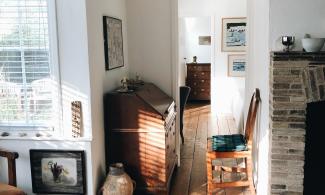 The interior of the Kettle's Yard house: a cottage with white walls. The sun shines brightly through a window, illuminating the many objects and paintings on display.