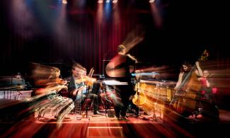 A large group of people performing with musical instruments on stage.