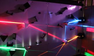 Lights of different colours shine in different directions against a wall.