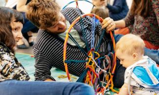 A man and a woman smiling with a toddler during a workshop at Kettle's Yard.