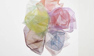 An artwork consisting of multiple pieces of mesh coated in bright colours and stuck together. The artwork is hung from the ceiling.