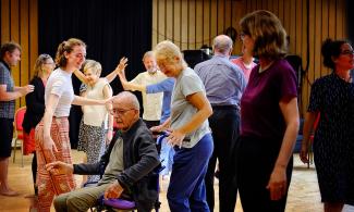 A group of people stand and dance together in a room at Cambridge Junction.