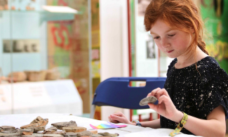 A young girl takes part in an object handling session trying to identify which are pieces of pottery and which are stones.