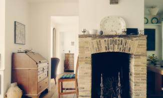 The Kettle's Yard house: a brightly lit cottage with exposed wooden beams and a large brick fireplace.