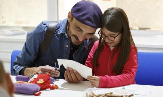Child with adult doing a paper craft activity. Photo by Mike Cameron.