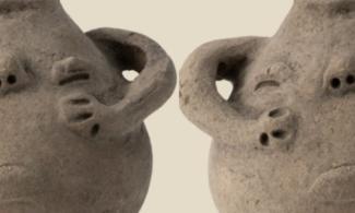 A pot with a grumpy looking face on one side with handles in the shape of arms.
