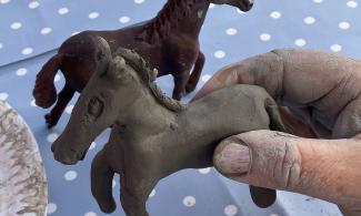 Clay horse sculpture held by a parent