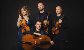 Quartetto Noûs posing with two violins, a viola and a cello against a dark background.
