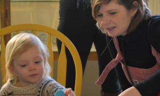 Two children play, behind them is a yellow chair
