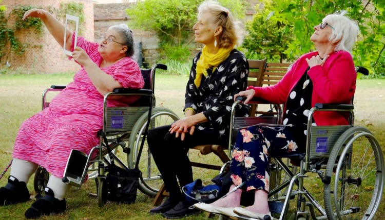 Age well session with 3 people sat under the trees at Jesus College Garden