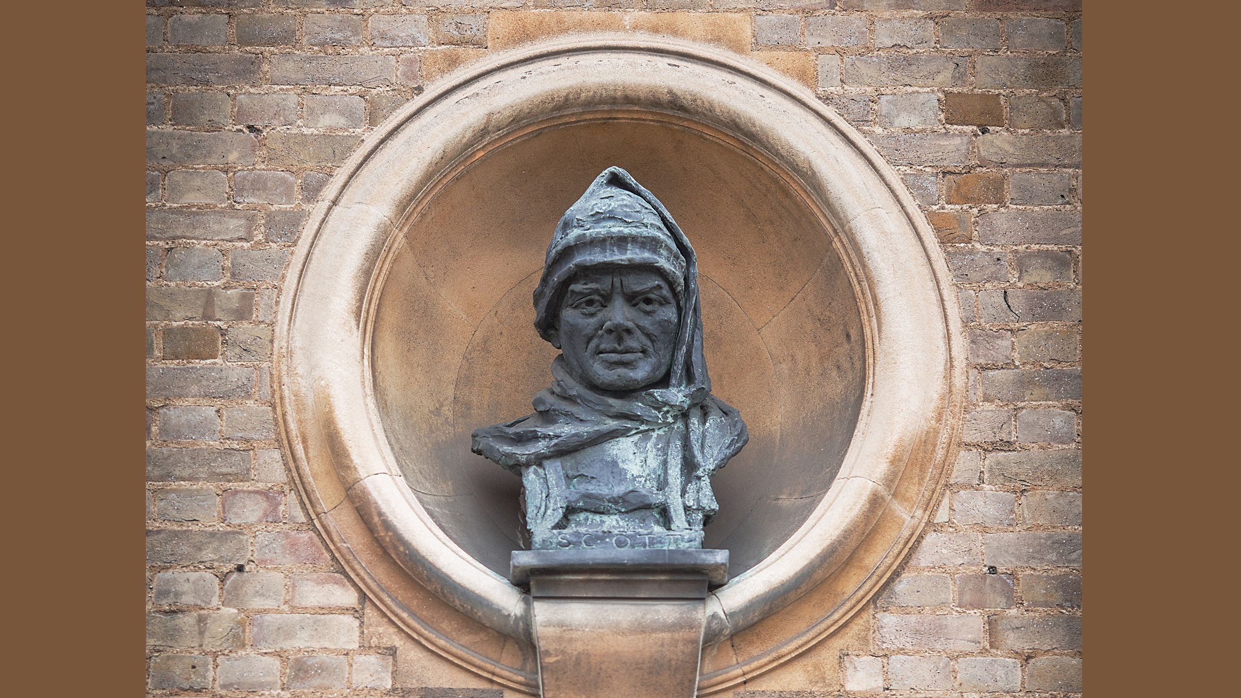 Cast bust of Captain Scott wearing sledging clothes set in a stonework on front of the SPRI building