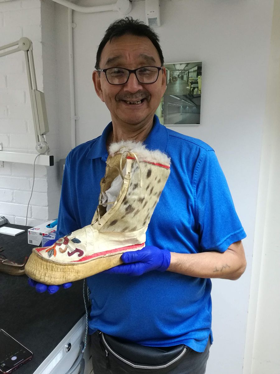 Iñupiaq artist Willy Topcock holds a seaskin boot from the Polar Museum's collections.