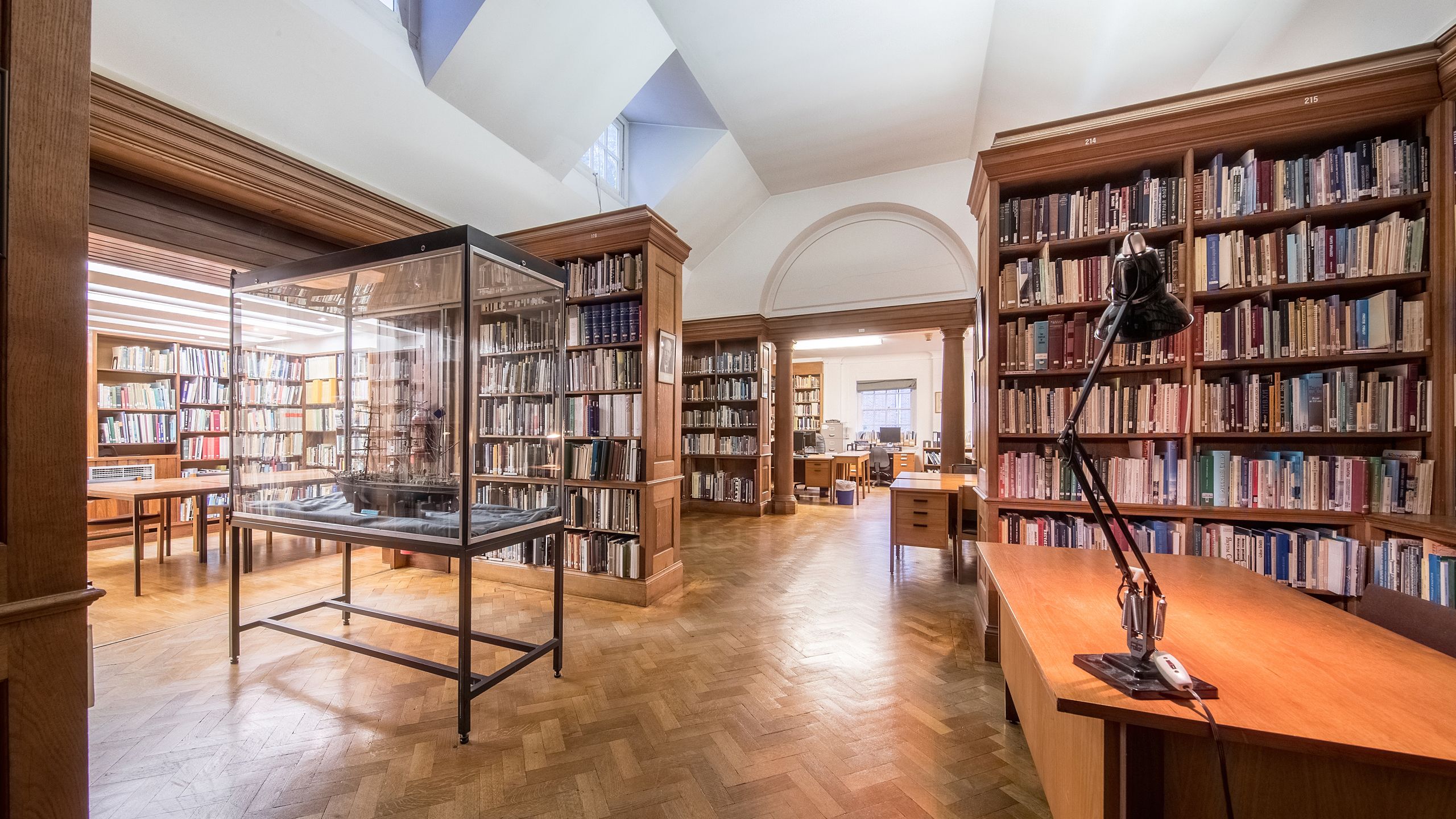 Image of the Polar Library, showing shelves of books, a model ship in a showcase and tables for people to work at.